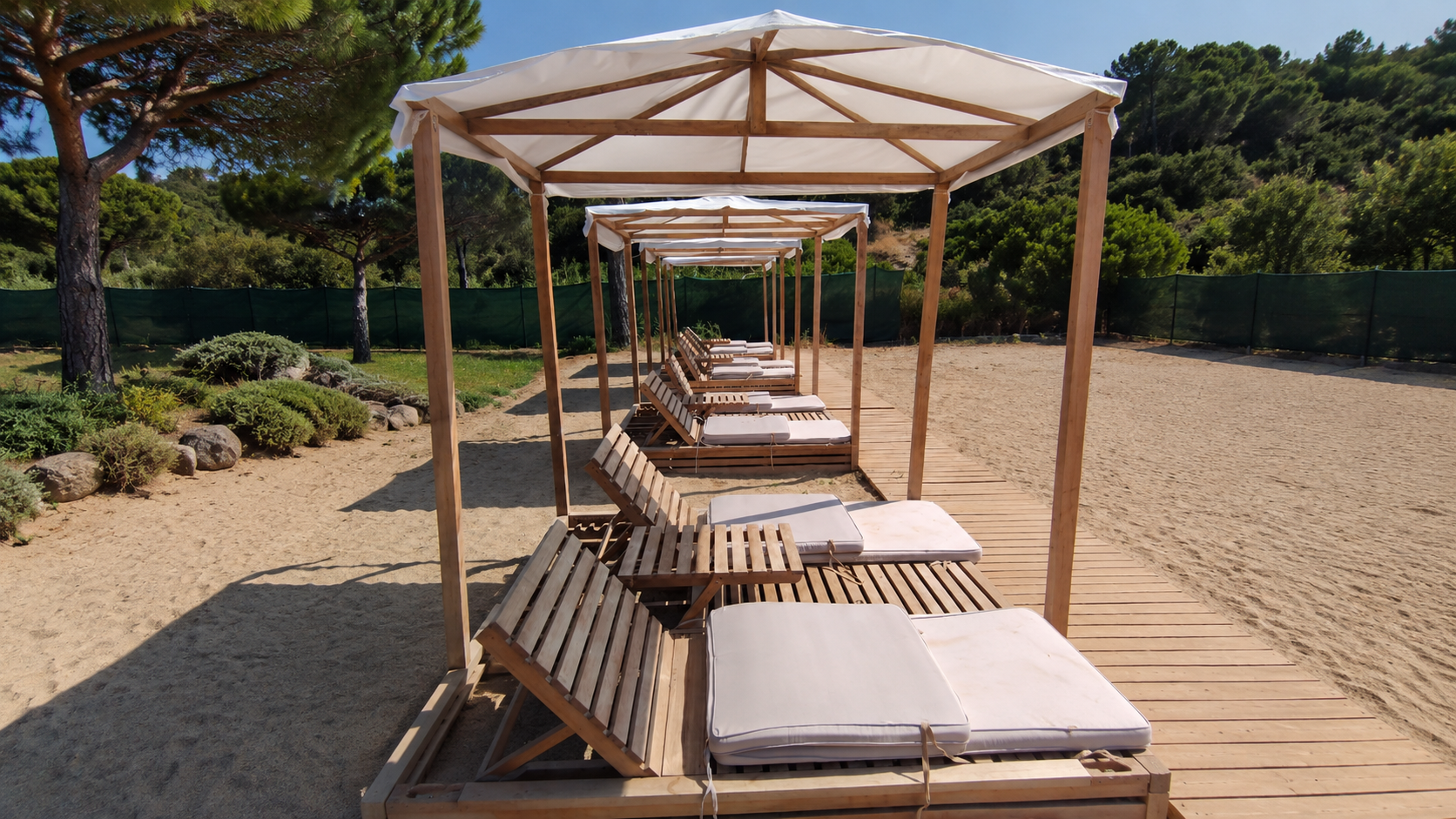 Private beach loungers beneath shaded cabanas